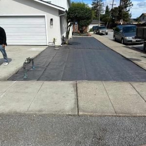 Clear, high-quality image of a freshly paved driveway with black asphalt in a suburban neighborhood.