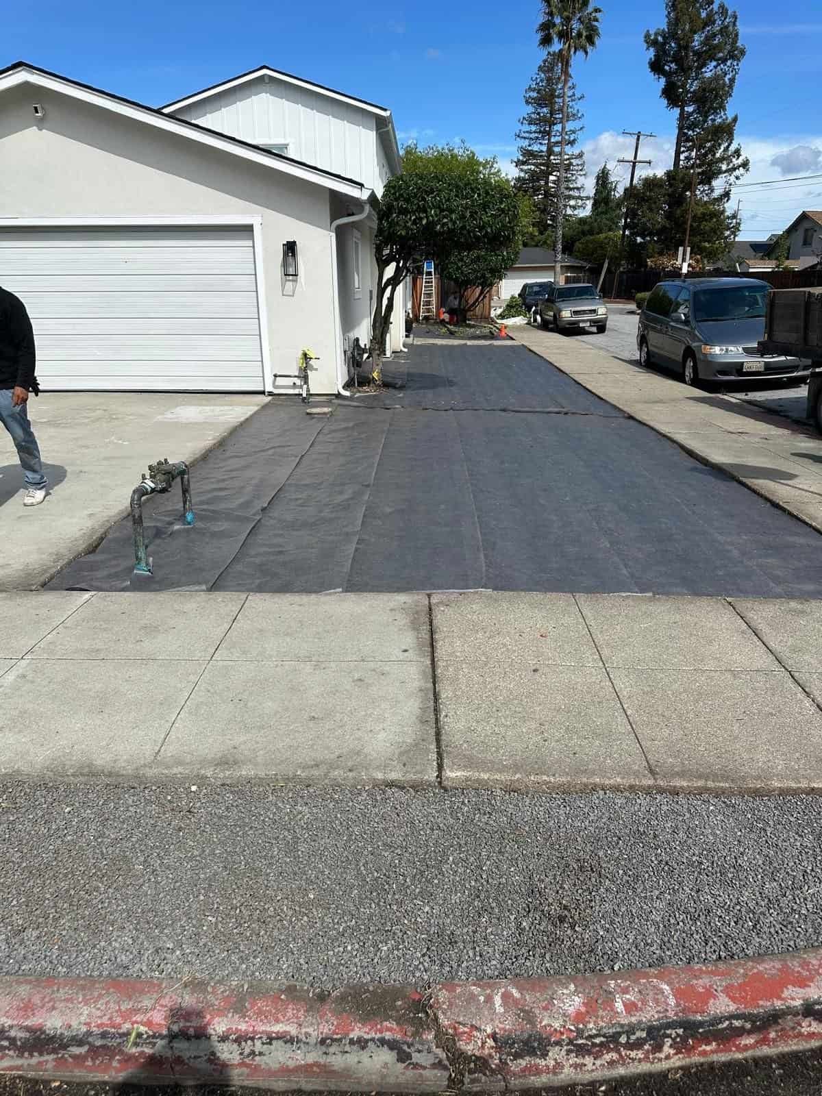 Clear, high-quality image of a freshly paved driveway with black asphalt in a suburban neighborhood.
